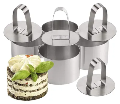 A set of stainless steel dessert rings with a small dessert in the foreground.