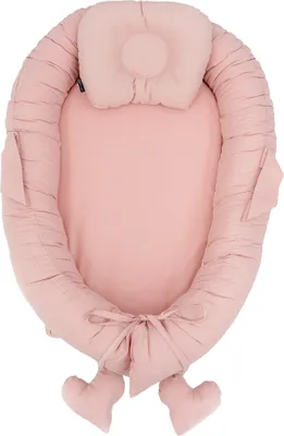 A pink baby nest with a small pillow attached.