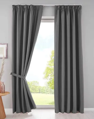 A pair of dark gray blackout curtains are shown hanging in front of a window, with one curtain tied back.