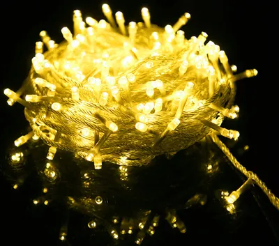 A tangled ball of yellow LED string lights on a reflective black surface.