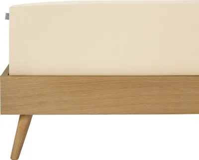 A close-up view of a bed frame with a cream-colored sheet.