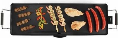 A top-down view of a black electric teppanyaki grill with various foods cooking on it.