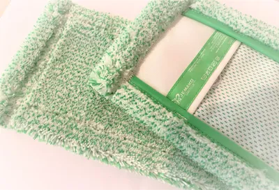 A close-up view of a green and white microfiber mop head, showing its texture and a label.