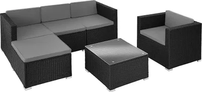 A modular rattan outdoor furniture set with grey cushions, including a sectional sofa, an ottoman, a coffee table, and an armchair, displayed on a white background.