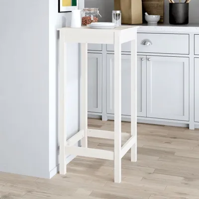 A white bar table placed next to kitchen cabinets.
