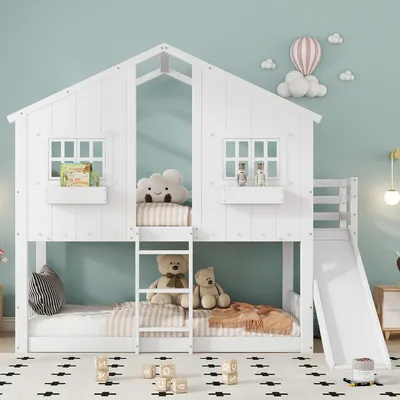 A white bunk bed shaped like a house with a slide, set up in a child's bedroom with toys and decorations.