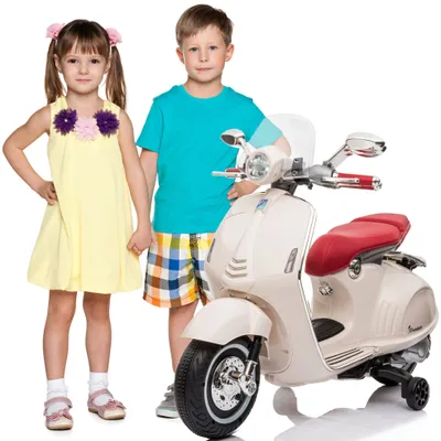 Two children stand next to a cream-colored electric scooter.