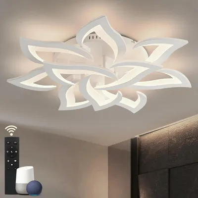 A modern white ceiling light fixture shaped like a flower, with integrated LED lighting. A remote control and smart home devices are visible in the foreground.