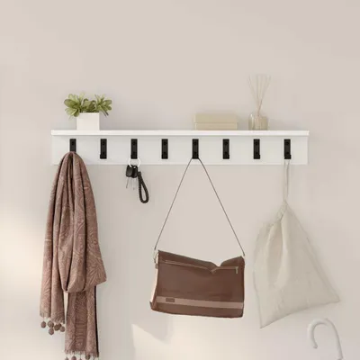 A white shelf with hooks mounted on a light-colored wall, displaying various items like a scarf, keys, and bags.