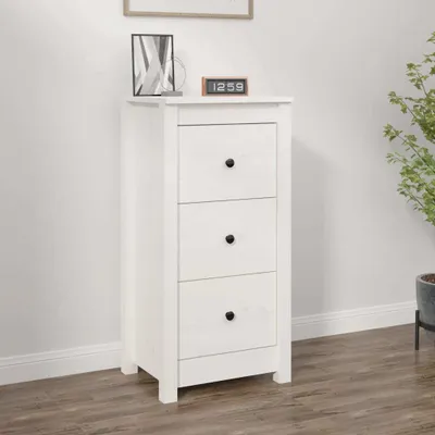 A white wooden chest of drawers with three drawers, placed against a white wall on a wooden floor. A small digital clock is on top of the chest.