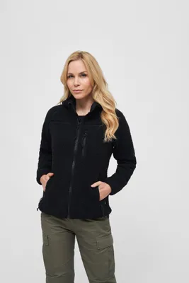 A woman is posing in front of a white background wearing a black fleece jacket and green cargo pants.