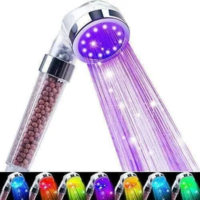 A close-up of a shower head with purple LED lights and water spraying out.