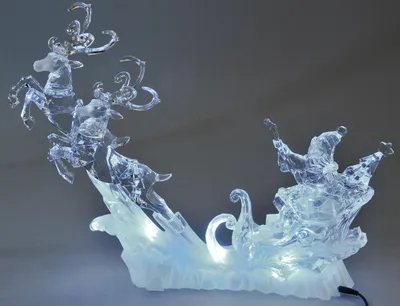 A clear acrylic Christmas decoration featuring Santa in a sleigh pulled by reindeer, illuminated by internal LED lights.