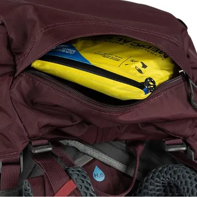 A close-up view of the top pocket of a backpack, revealing a yellow medical kit inside.