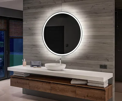 A modern bathroom vanity with a round LED mirror, sink, and wooden cabinets.