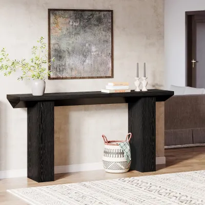 A black console table is set up in a living room with a painting on the wall and a basket on the floor.