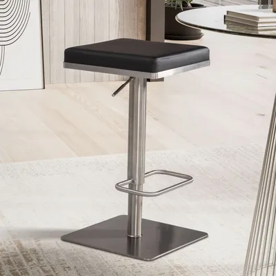 A modern bar stool with a black seat and a silver metal base and stem, placed on a rug in a room.