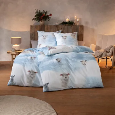 A bedroom scene with a bed made up with sheep-themed bedding.