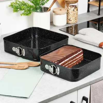 A kitchen counter with baking pans and a cake.
