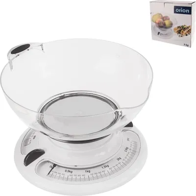 A kitchen scale with a clear bowl is displayed against a white background. A product box is visible in the upper right corner.