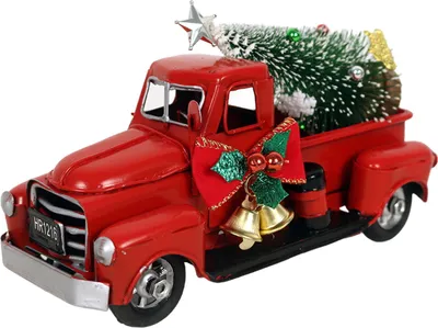 A red vintage truck carrying a Christmas tree, decorated with a red bow and bells.
