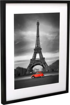 A framed picture of the Eiffel Tower with a red car in the foreground.