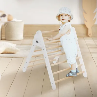 A child is playing on a wooden climbing triangle indoors.