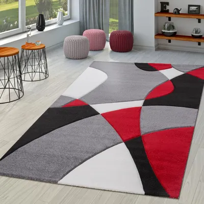 A modern living room with a geometric rug, side tables, and poufs.