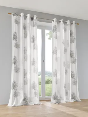 Curtains hanging in front of a window with a view of a landscape.
