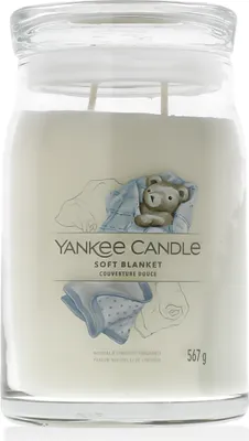 A Yankee Candle jar with a label showing a teddy bear wrapped in a blanket.