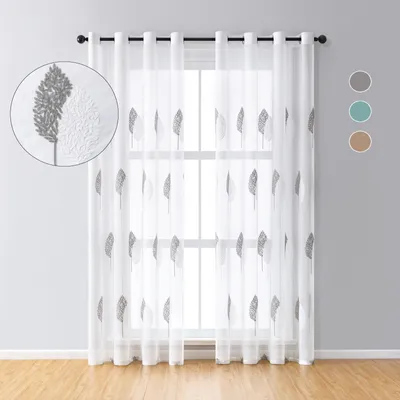A sheer curtain with a leaf pattern hanging in front of a window.