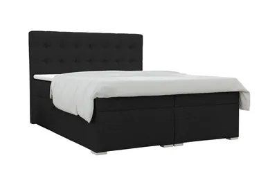 A black upholstered box spring bed with a white duvet is shown against a white background.