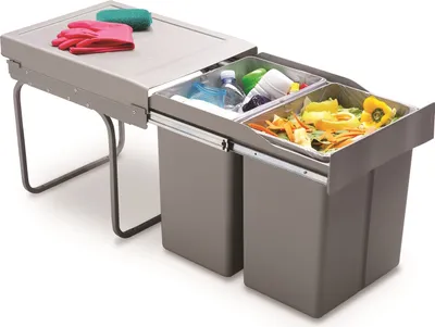 A pull-out kitchen waste bin system with two compartments, shown with cleaning gloves and a sponge on top.