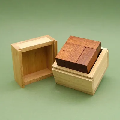 Geöffnete Cabrio Holzpuzzle-Box mit passgenauen dunklen Holzteilen im Inneren, auf grünem Hintergrund.