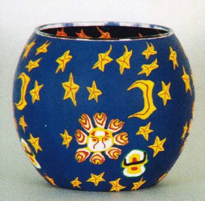 Ein Windlicht aus Fimo-Glas das mit gelben Sternen, Monden und einer Sonne verziert ist.