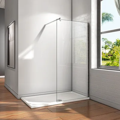 A modern walk-in shower enclosure with a glass panel and a white shower tray, set against a white tiled wall and a wooden floor, with natural light coming from a window.