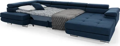 A navy blue sectional sofa is shown with a portion of it pulled out to reveal a bed, complete with bedding and pillows.