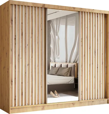 A bedroom scene reflected in a mirrored wardrobe door, showing a bed with pillows and a bedside table.