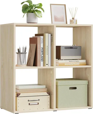 A light oak colored cube shelf unit with books, a plant, a picture frame, and storage boxes.