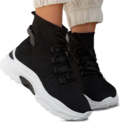 A pair of black high-top sneakers with white soles, worn by a person.