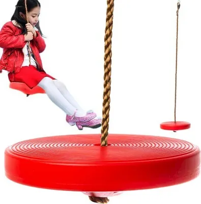 A young girl is sitting on a red disc swing, with another red disc swing in the background.