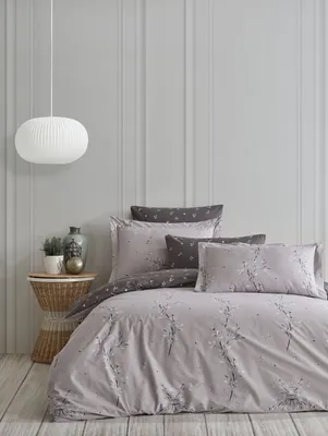 A neatly made bed with grey bedding and pillows, set against a light grey paneled wall.