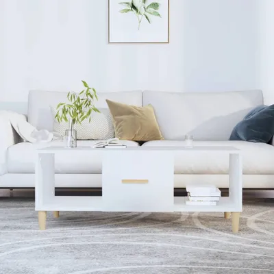 A white coffee table with a drawer and open shelving is placed in a living room setting in front of a white sofa.