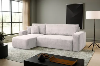 A modern living room with a beige sectional sofa, a large window, and a black coffee table.