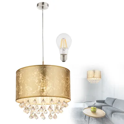 A gold pendant light with crystal accents and a separate light bulb are shown against a white background. A blurred living room scene with a sofa and coffee table is visible in the background.