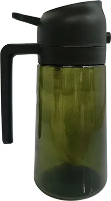 A green glass oil sprayer with a black lid and handle against a white background.
