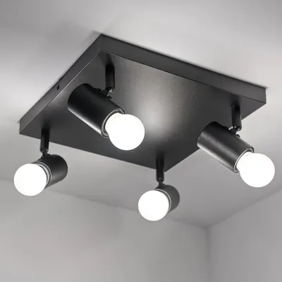 A black, square ceiling light fixture with four adjustable spotlights is shown against a white ceiling and wall.
