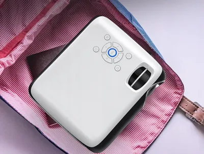 A white projector is placed inside a bag with a red and white striped lining.