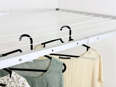 A close-up view of a ceiling-mounted clothes drying rack with clothes hanging on it.