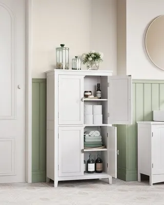 A white bathroom cabinet with its doors open, displaying various items inside, set against a light green and cream wall.